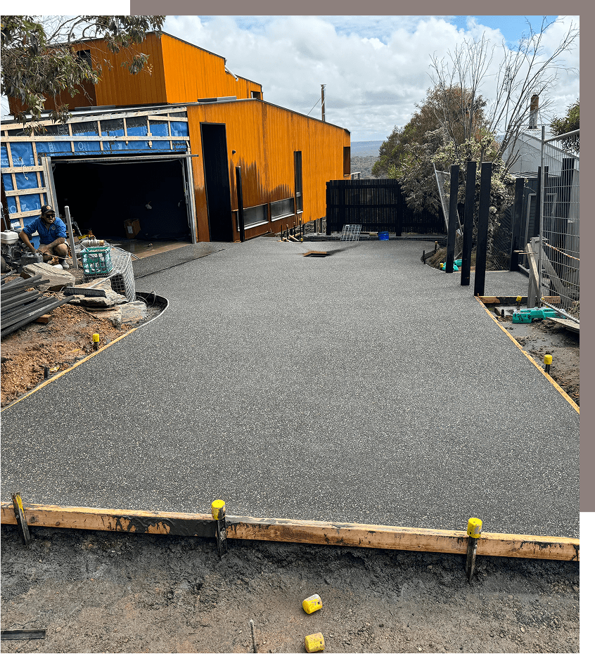Concrete driveway construction near orange building.