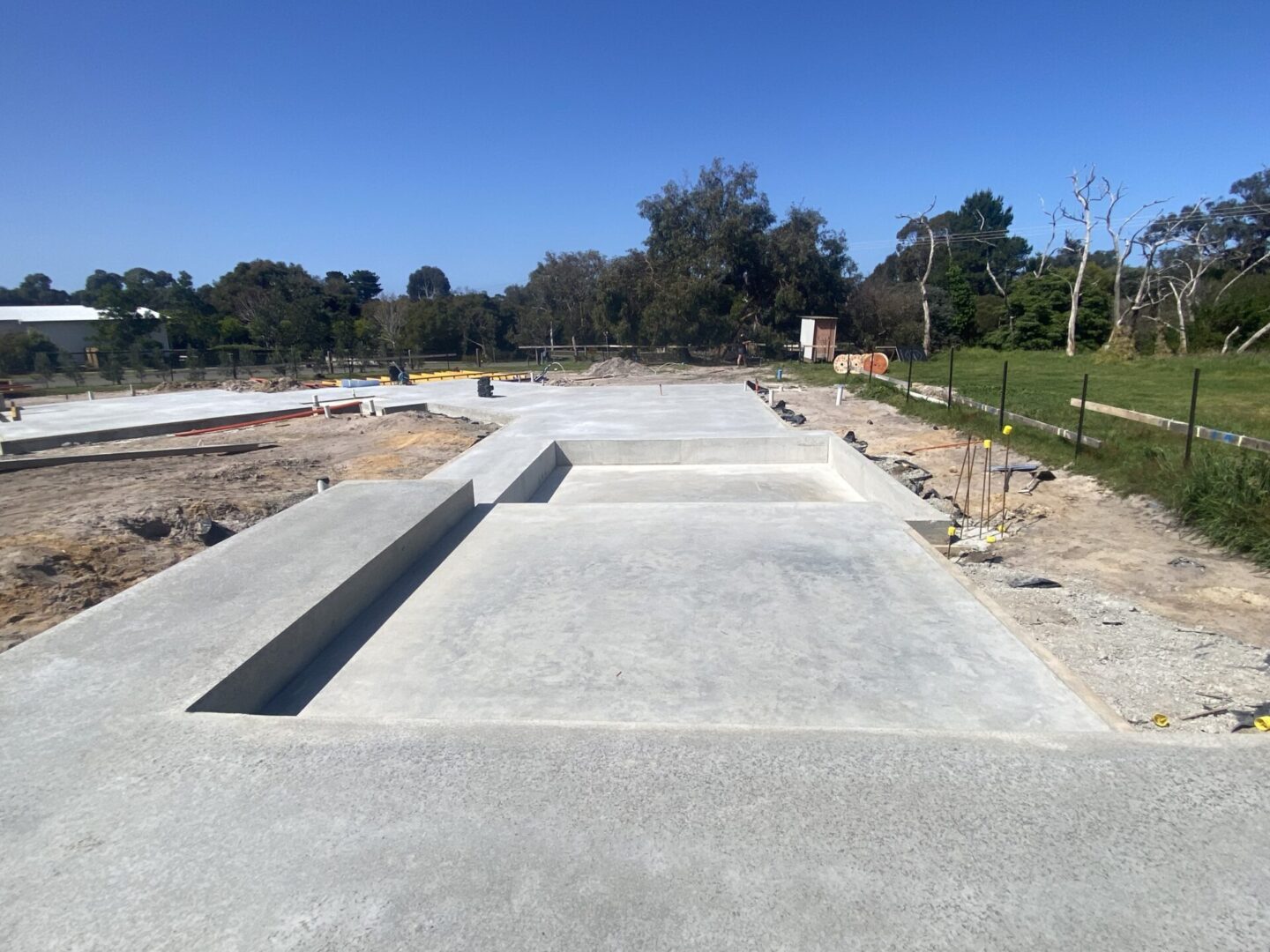 Concrete skatepark under construction on sunny day.