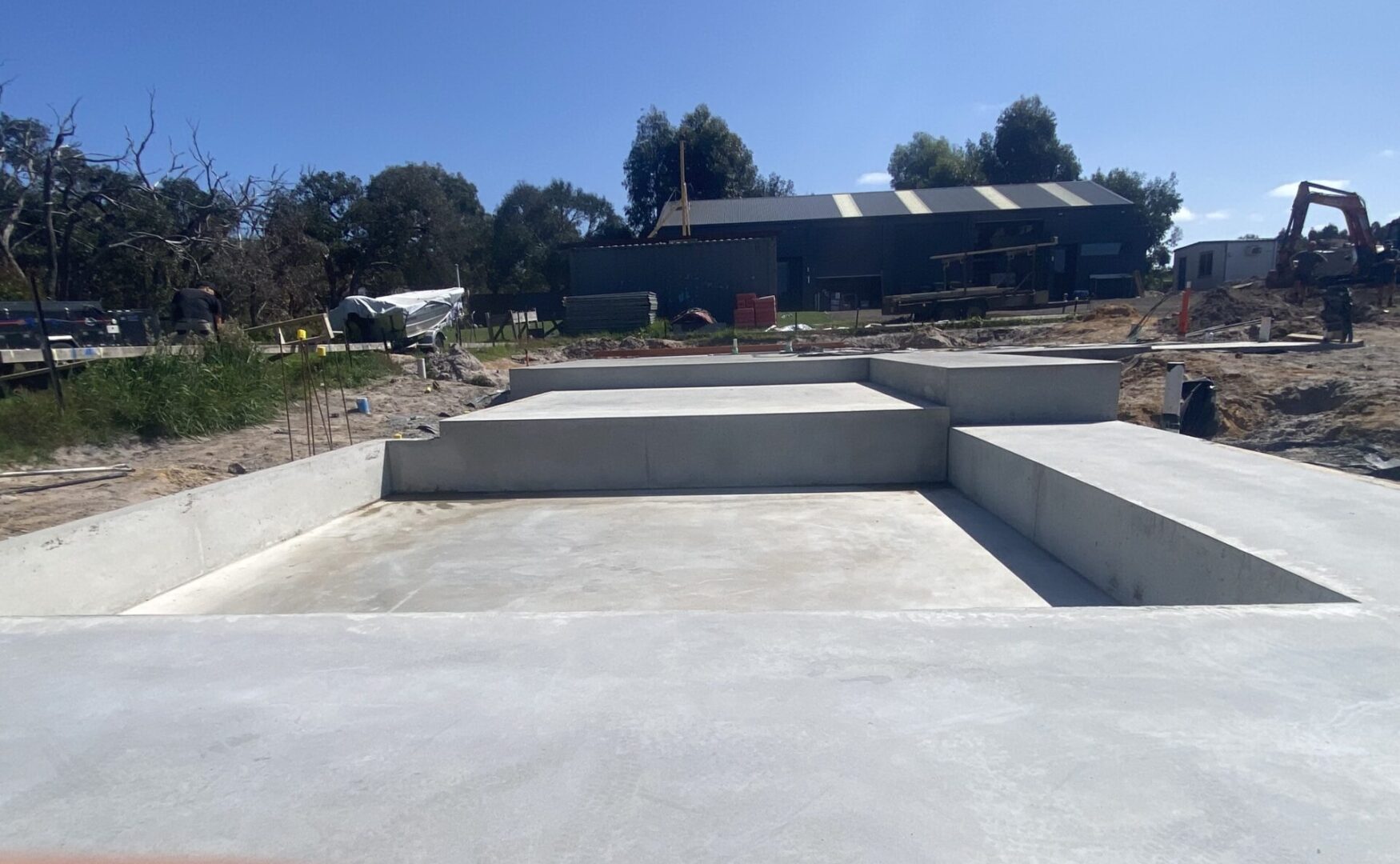 Concrete construction site with building and trees.